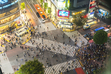 High angle view of urban street lined with illuminated buildings, pedestrians walking on pedestrian crossings. - MINF06585