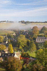 Landschaft mit Bäumen und traditionellen Häusern in einem Dorf im Morgennebel. - MINF06594