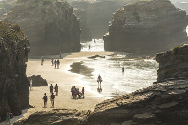 People on sandy beach surrounded by rocks. - MINF06613