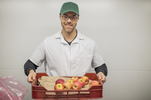 Arbeiter hält Apfelkiste, lizenzfreies Stockfoto