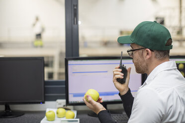 Worker using walkie talkie while working at computer - ZEF15932