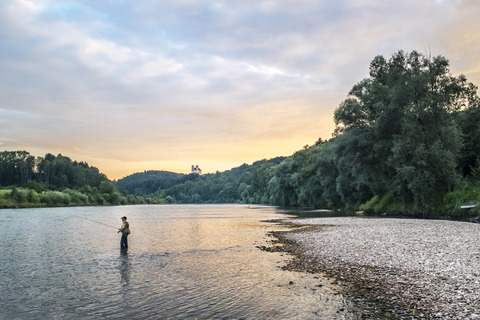 Deutschland, Oberbayern, Burghausen, Salzachtal, Fliegenfischer bei Sonnenuntergang, lizenzfreies Stockfoto