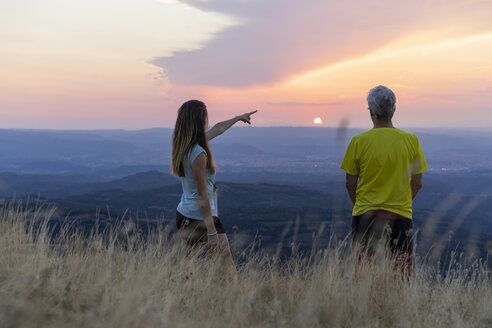 Spanien, Katalonien, Montcau, älterer Vater und erwachsene Tochter betrachten die Aussicht von der Spitze des Hügels bei Sonnenuntergang - AFVF01359
