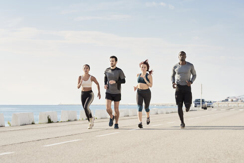 Group of sportspeople jogging at harbour - JNDF00026