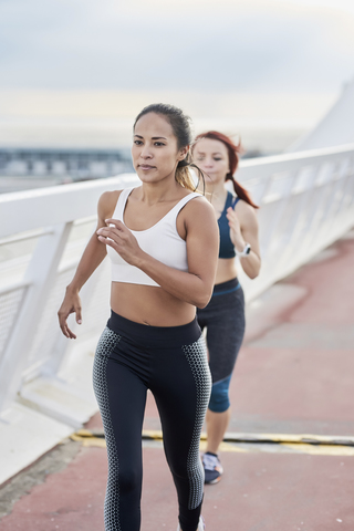 Female athletes running on a bridge stock photo