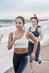 Female athletes running on a bridge - JNDF00033