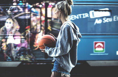 Junge Frau geht mit einem Basketball in der Hand und einem Trainer im Rücken. - MINF06640