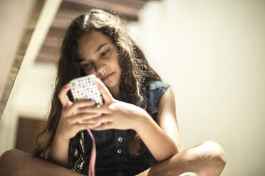 Low angle shot of a girl looking at a mobile phone screen. - MINF06680