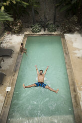 High angle shot of a man jumping backwards into a swimming pool. - MINF06682