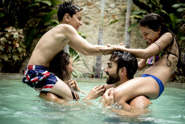 Zwei Kinder, die auf den Schultern von Erwachsenen sitzen, kämpfen in einem Schwimmbad. - MINF06684