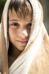 Close up of a boy wrapped in a towel smiling into shot. - MINF06687