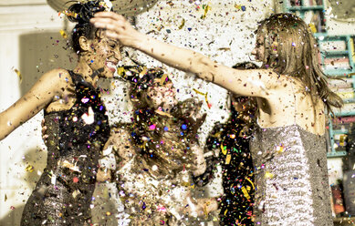 Eine Gruppe junger Frauen feiert auf einer Party in einem Dunst aus fallendem Glitzerkonfetti. - MINF06722