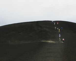A black volcanic cone hillside in the Craters of the Moon national monument and preserve in Butte County Idaho. People walking on the slope. - MINF06757