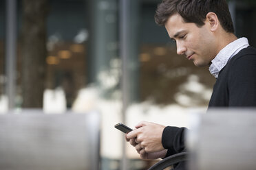 Summer in the city. People outdoors, keeping in touch while on the move. A man sitting on a bench using a smart phone. - MINF06768