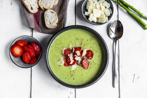 Grüne Spargelcremesuppe mit Erdbeeren, Parmesan und Baguette, lizenzfreies Stockfoto