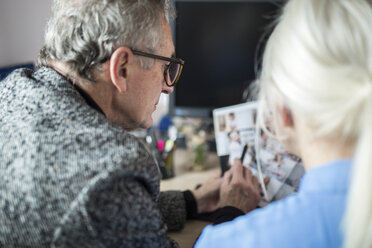 Zwei ältere Kollegen arbeiten zusammen am Schreibtisch im Büro und prüfen Fotos - AWF00176