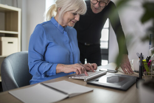Two senior colleagues working together at desk in office - AWF00185