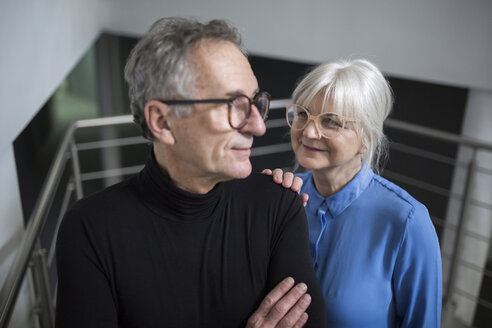 Senior woman supporting senior businessman on office stairs - AWF00189