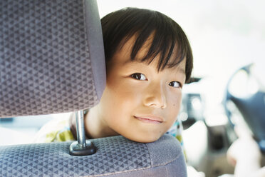 Boy with black hair sitting in a car, looking at camera. - MINF06836