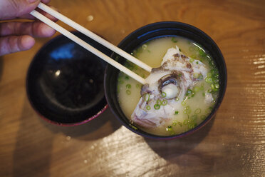 Nahaufnahme einer Schüssel mit Suppe und einem Stück Fisch in einem japanischen Sushi-Restaurant. - MINF06859