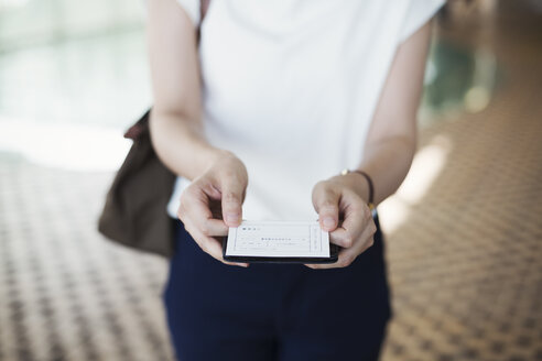 Close up of woman standing in subway station, holding ticket, Tokyo commuter. - MINF06867