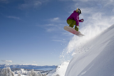 Eine Snowboarderin fährt an einem sonnigen Tag in Kalifornien einen 540er im Backcountry. - AURF00010