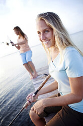 Smiling woman with family fishing on dock over lake stock photo