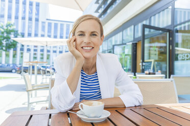 Lächelnde blonde Geschäftsfrau in einem Straßencafé - TCF05553