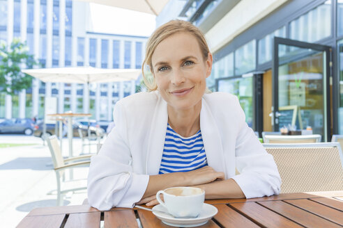 Smiling blond businesswoman at sidewalk cafe - TCF05554