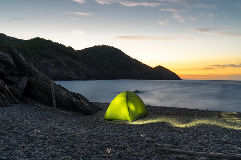 Spanien, Katalonien, Costa Brava, grünes Zelt am steinigen Strand am Abend - AFVF01374