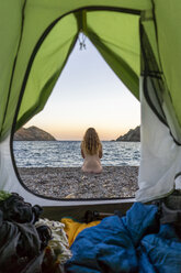 Spanien, Katalonien, Costa Brava, nackte Frau sitzt am Strand, Blick aus dem Zelt - AFVF01377