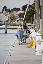 Junges Paar trägt Seekajaks auf dem Dock, Mystic Seaport, Connecticut, USA. - AURF00043