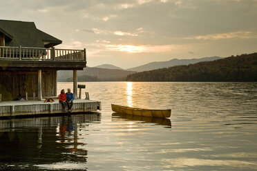 Junges Paar sitzt am frühen Morgen mit Kanu auf dem Steg, Lake Placid, New York, USA. - AURF00045