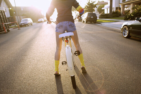 Junge Frau mit gelben Socken und Kapuzenpulli bereitet sich auf das Fahren mit einem Cruiser-Fahrrad vor. - AURF00057