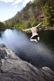 Junger Mann springt von Felsklippen in eine Lagune im High Falls Park, Geraldine, Alabama. - AURF00068