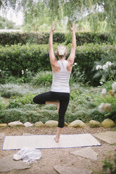 Blond woman doing yoga in a garden. - MINF06931