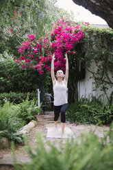 Blonde Frau beim Yoga in einem Garten. - MINF06932