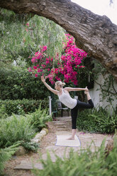 Blonde Frau beim Yoga in einem Garten. - MINF06937