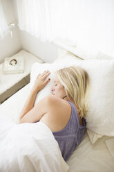 Blonde Frau schläft in einem Bett mit weißer Bettwäsche. - MINF06950