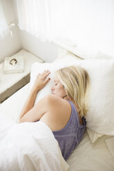 Blonde woman sleeping in a bed with white linen. - MINF06950