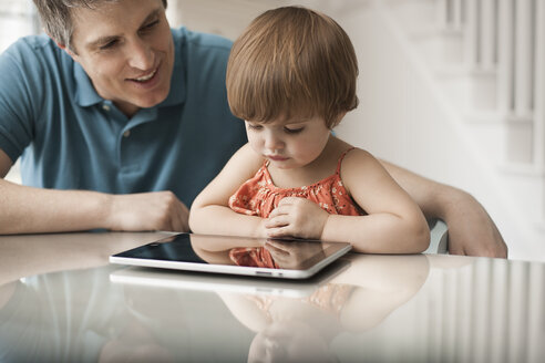 A father and his daughter looking at a digital tablet, using the touch screen. - MINF06987