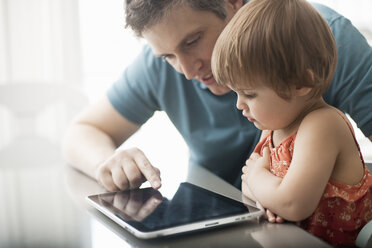 Ein Vater und seine Tochter sehen sich ein digitales Tablet an und benutzen den Touchscreen. - MINF06988