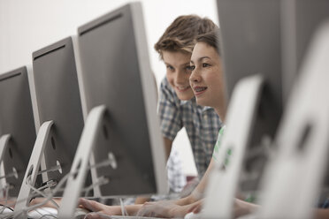 Ein Computerraum in einer Schule mit einer Reihe von Bildschirmen und zwei jungen Menschen, die aufmerksam auf den Bildschirm schauen. - MINF07003