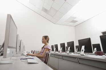 A school room, a computer lab with rows of screens and seating. A young person seated working at a terminal. - MINF07010