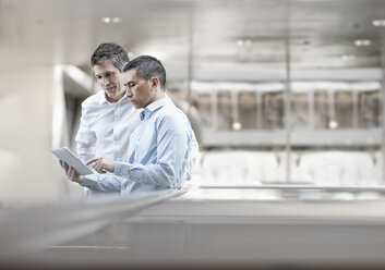 Zwei Männer, Geschäftskollegen, schauen auf einen digitalen Tablet-Bildschirm. - MINF07021