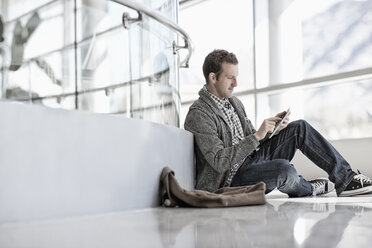 A man sitting down using a digital tablet. - MINF07025