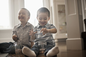 Zwei Kinder spielen mit Münzen und lassen sie in Gläser fallen. - MINF07035
