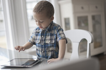 Ein kleines Kind sitzt an einem Tisch und benutzt ein digitales Tablet mit Touchscreen. - MINF07036