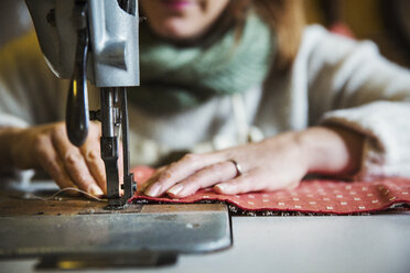 Upholstery workshop. A woman seated working with an industrial sewing machine, stitching fabric. - MINF07051