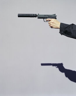 Detail eines Mannes, der mit einer Handfeuerwaffe mit Schalldämpfer zielt - MINF07072